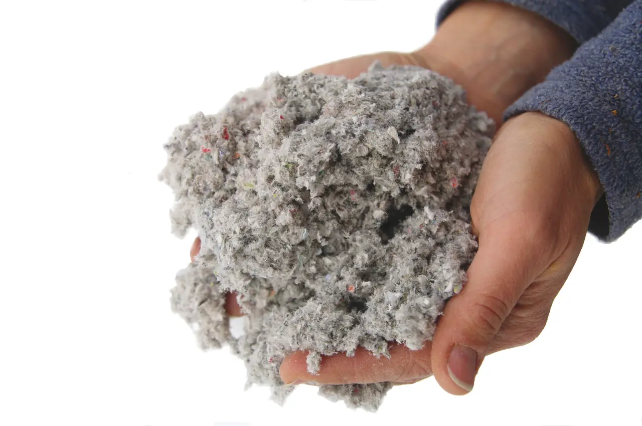 Två händer håller en näve gråvit cellulosafiber